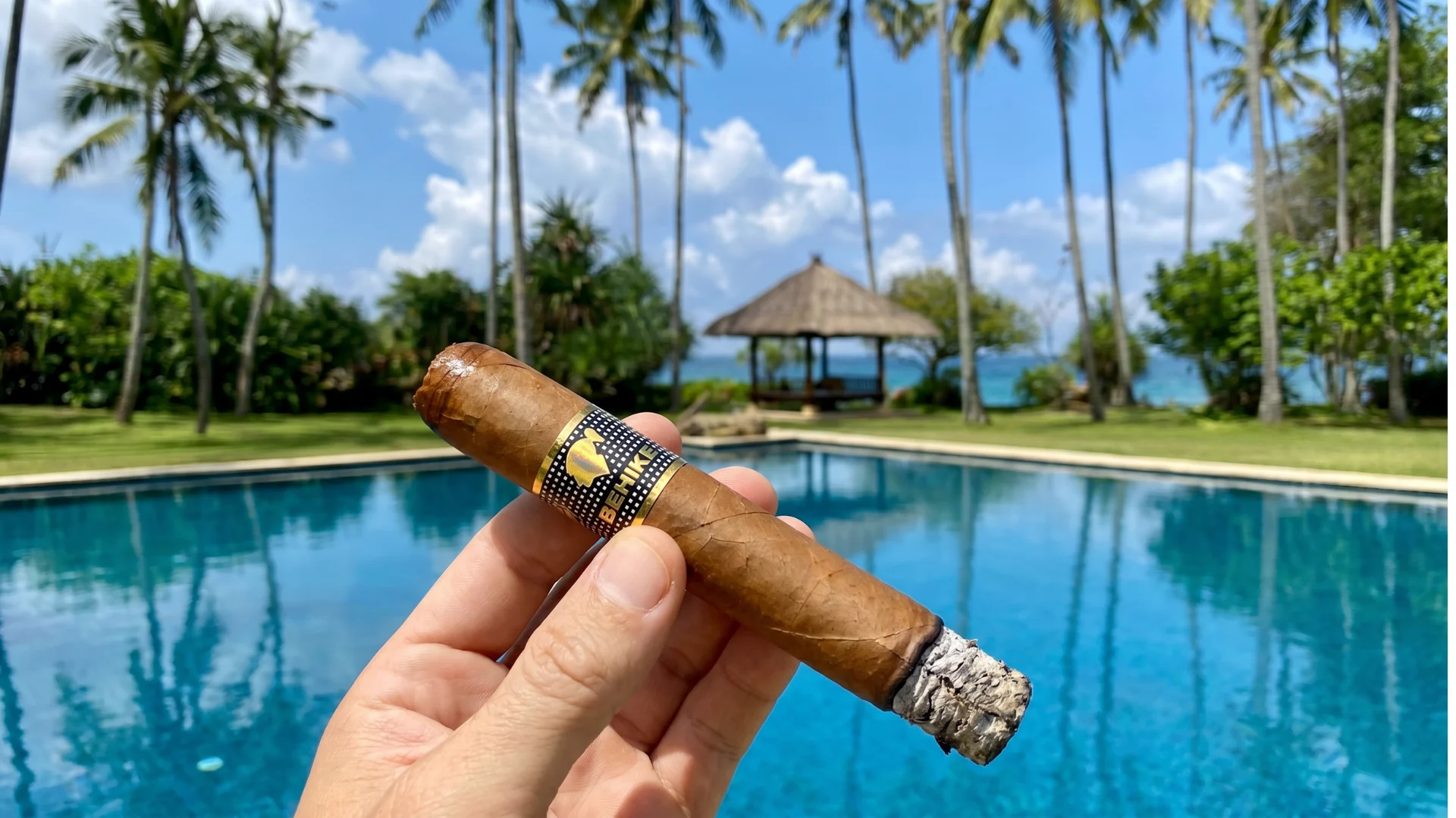 Hand holding an authentic Cohiba Cuban cigar by a tropical Havana pool